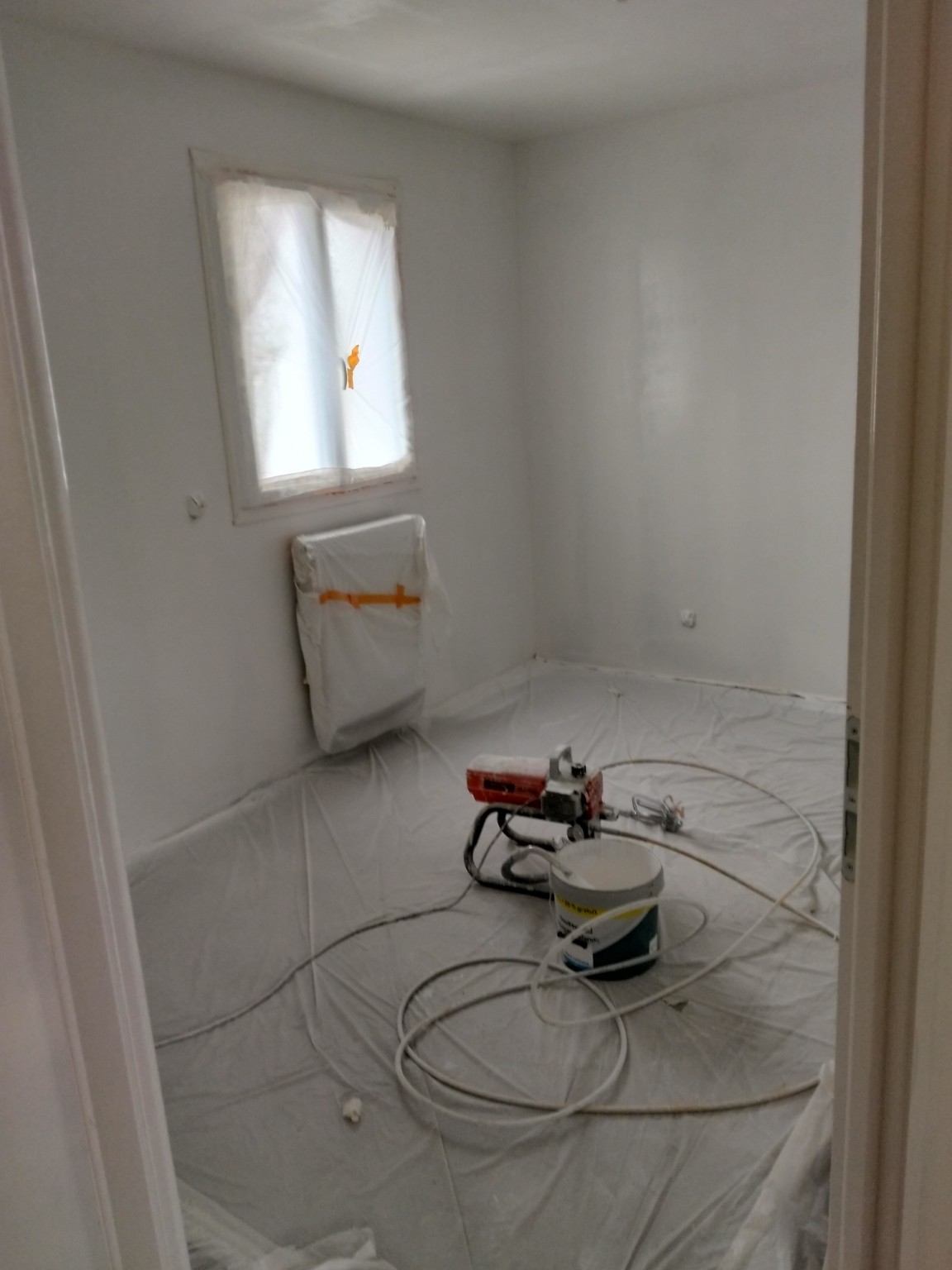Pièce protégée avec bâches avant application de peinture au pistolet